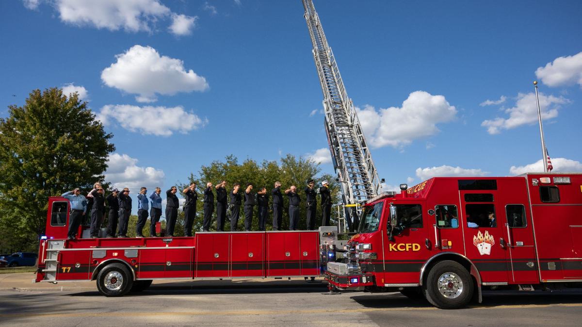Firefighters stand atop a firetruck and salute as a truck carrying the casket of KCFD firefighter Kyle Brinker drives by the Firefighter’s Memorial Fountain Wednesday, Sept. 25 in Kansas City.