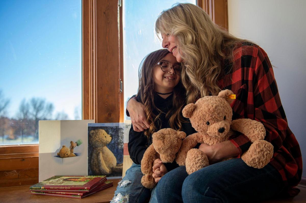 Phyllis Harris, author and illustrator of “The Gift Shop Bear,” shares a hug with her granddaughter Eliana Hernandez at her home studio in Raymore. Eliana was the inspiration behind the book after she found her mother’s old teddy bear stored in a toy box in the attic.