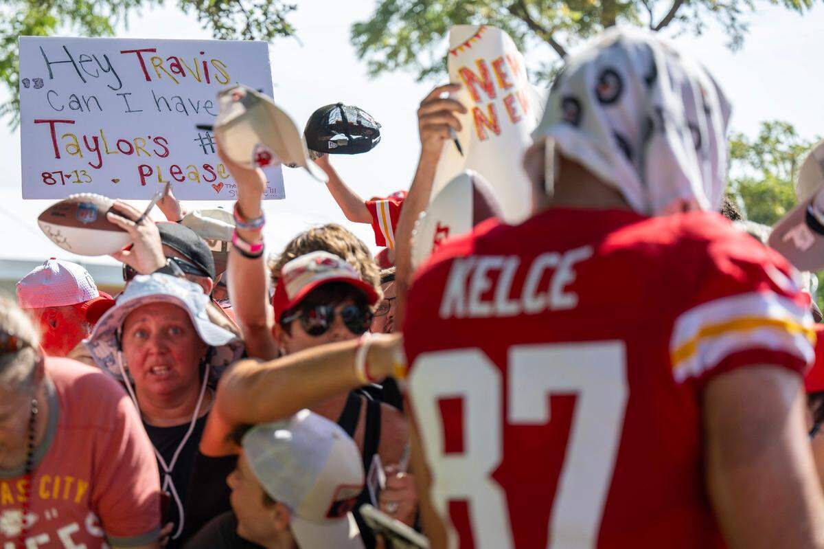 A sign reads “Hey Travis, can I have Taylor’s number, please?” among a sea of fans as Kansas City Chiefs tight end Travis Kelce signs autographs at training camp in St. Joseph.