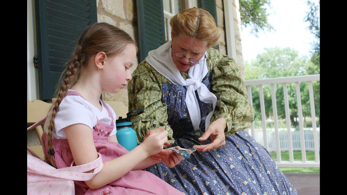 Cecelia Roper, 6, gets a lesson in how to sew on a button from historical interpreter Kim Payton at the Mahaffie Stagecoach Stop and Farm Sept. 1.