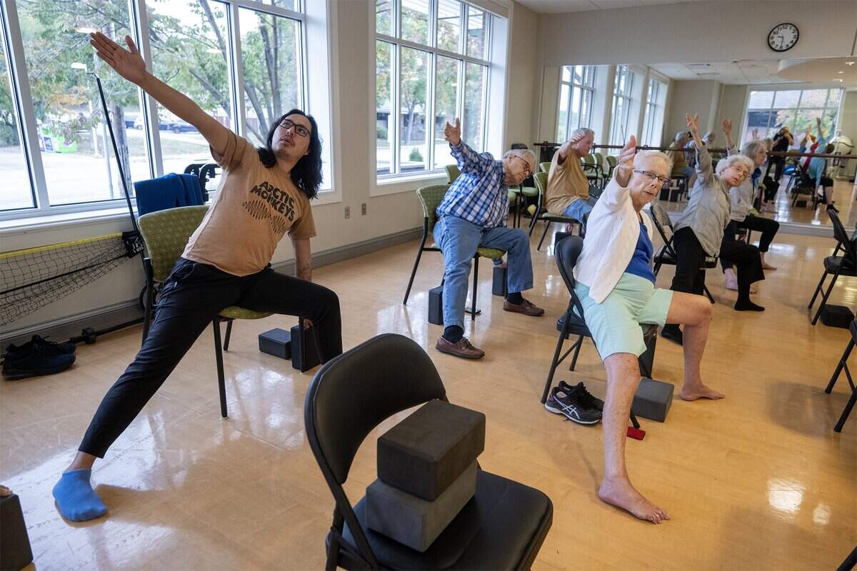 Naren Palomino Pardo, left, a graduate piano student at the University of Missouri–Kansas City Conservatory, participates in an ageless yoga class at Claridge Court on Tuesday, Oct. 14, in Prairie Village. Palomino Pardo is an artist-in-residence and lives in the senior community.