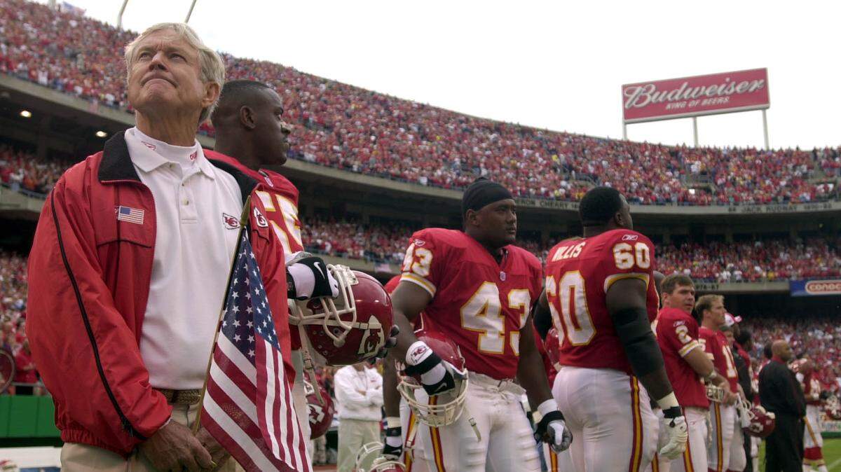 Chiefs coach Dick Vermeil watches the video board while holding an American flag during an emotional preg-ame ceremony before Kansas City’s home game against the New York Giants on Sept. 23, 2001 at Arrowhead Stadium.