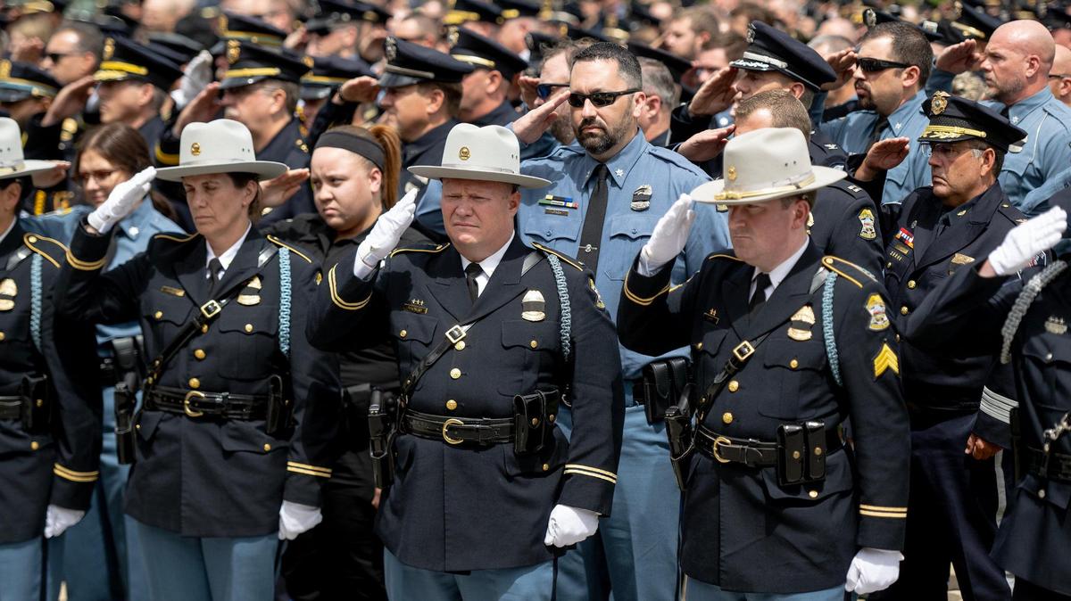 Hundreds of law enforcement officers salute as the remains of fallen Fairway police officer Jonah Oswald are carried outside of the Westside Family Church following a funeral on Monday, Aug. 14, 2023, in Lenexa, Kan.