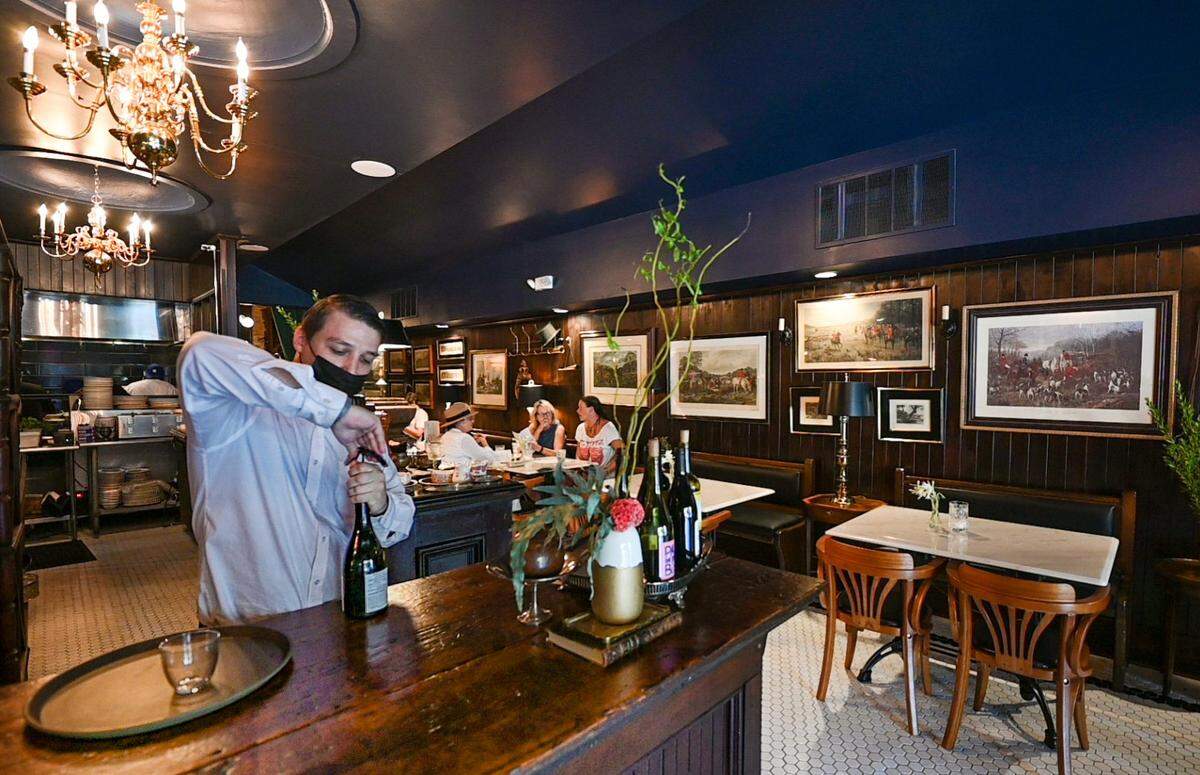 Lead server Brandon Chester uncorked a bottle of wine during the lunch rush at Tailleur, now open at 3933 Main St.