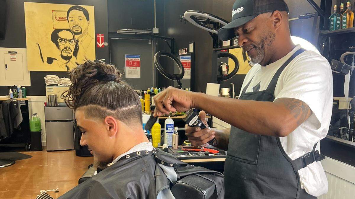 Kansas Jayhawks linebacker Jayson Gilliom receives a haircut from Tim Nelson at Watson’s Barbershop in Lawrence.