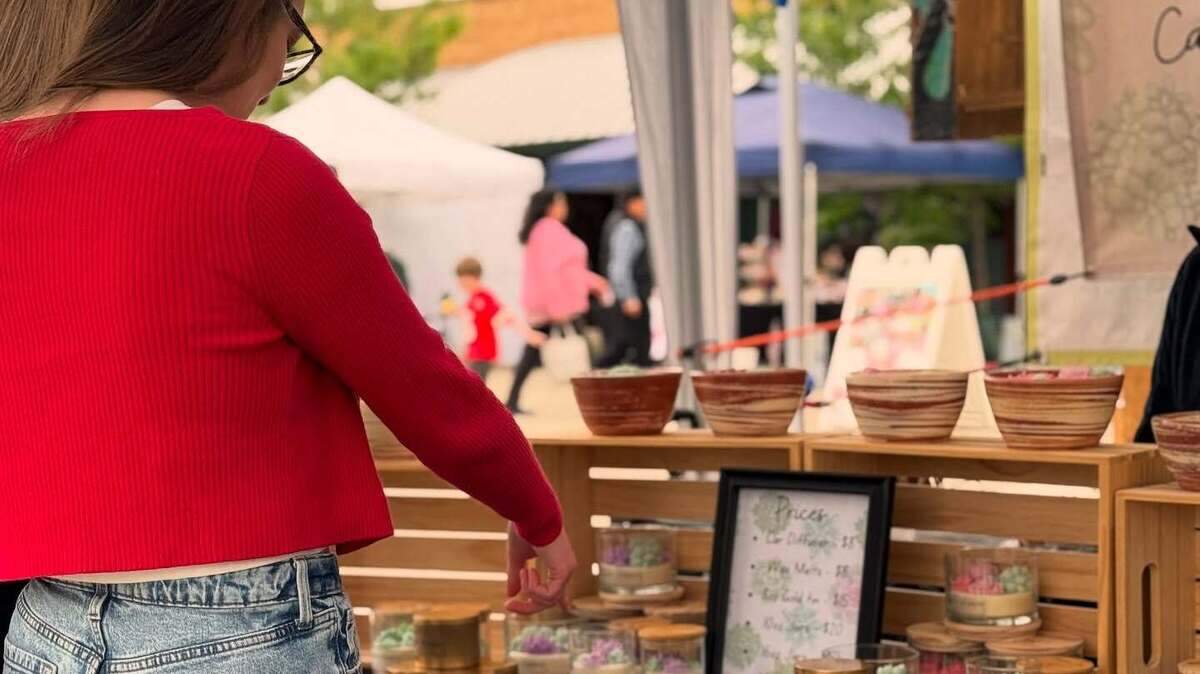 A customer shops at an artist vendor booth.
