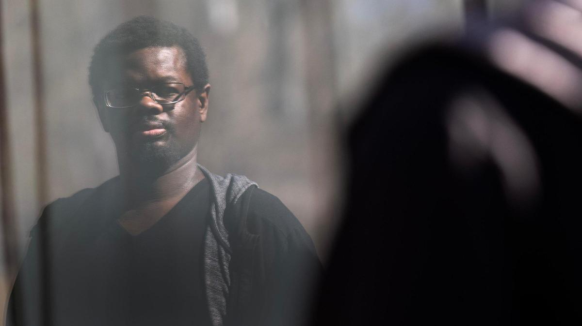 Jasper Hudgins-Bradley stands for a photo at his home as his reflection appears in a nearby window on Thursday, Feb. 27, 2025, in Overland Park.