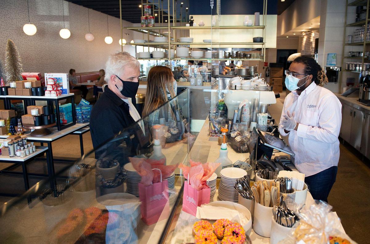 Despite the COVID-19 pandemic and the limits on occupancy, business is booming at Caffetteria Modern Cafe & Marketplace in Prairie Village where Darius Grayson, right, helped customers during lunch on Thursday.