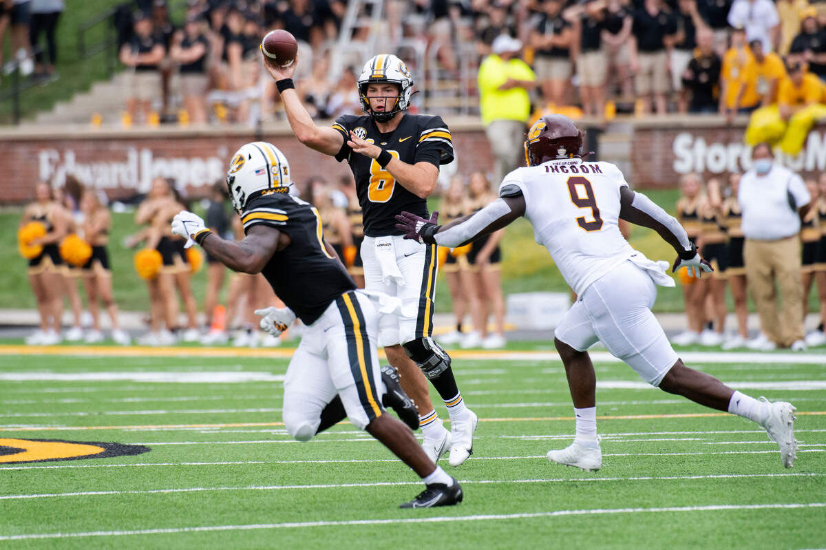 Missouri quarterback Connor Bazelak, center, throws a pass to teammate Tyler Badie, left, past Central Michigan defensive lineman Thomas Incoom, right, during the first half of an NCAA college football game Saturday, Sept. 4, 2021, in Columbia, Mo. (AP Photo/L.G. Patterson)