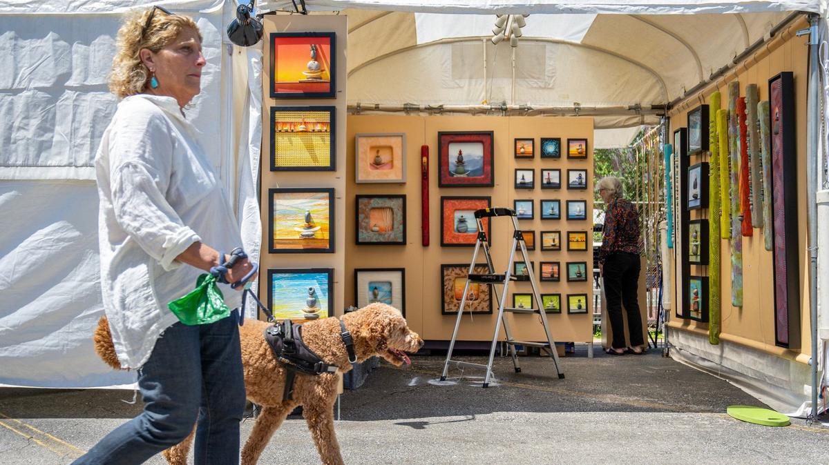 A visitor walks their dog past the booth of David Gilbertsen and Joy Wallace from Amherst, Wisconsin, Friday before the start of the Brookside Art Annual.