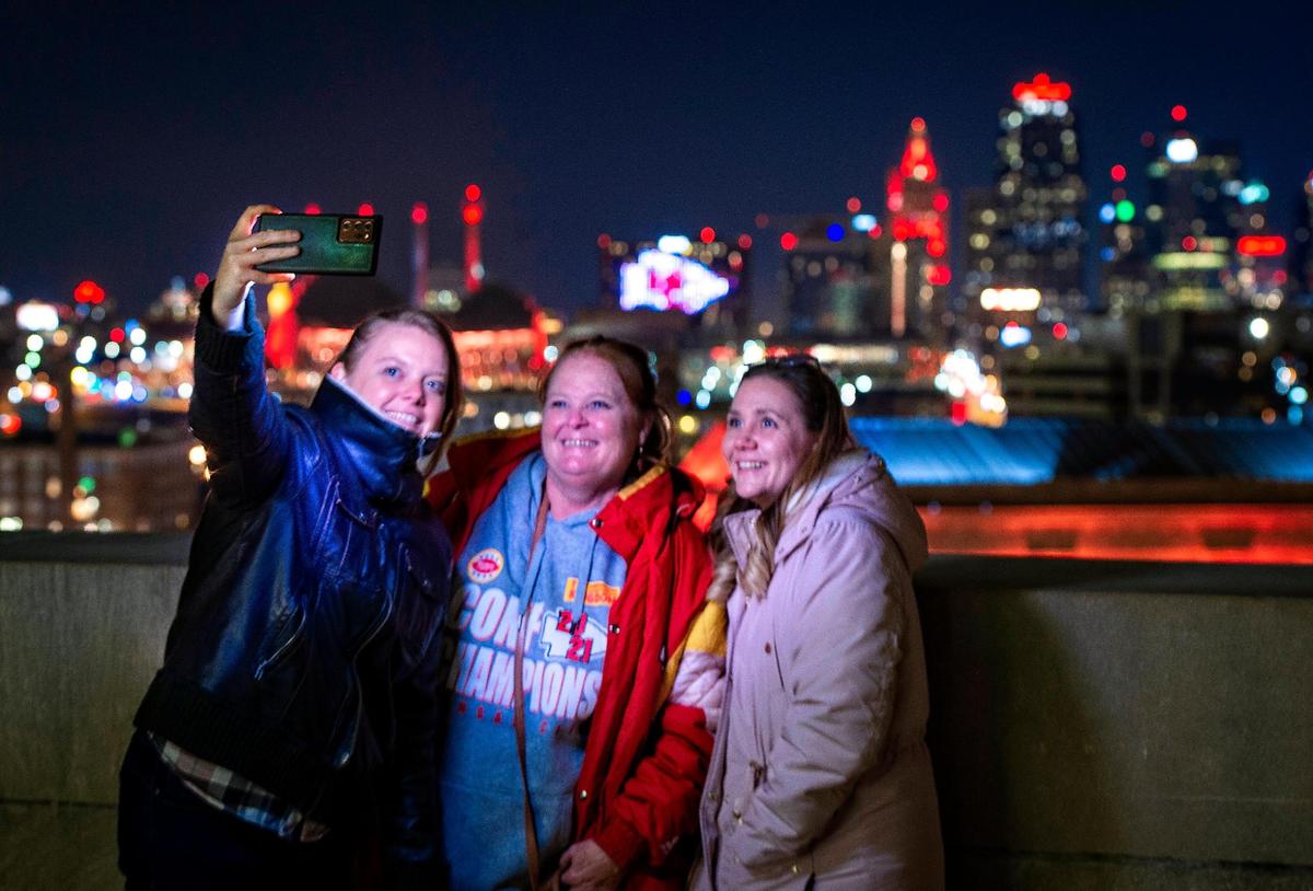 Leiani Haug, left, takes a photo of her mother Debbie Haug, center and her sister Nicole Haug from the deck of the Liberty Memorial on Jan. 29 against a backdrop of buildings lit in red.