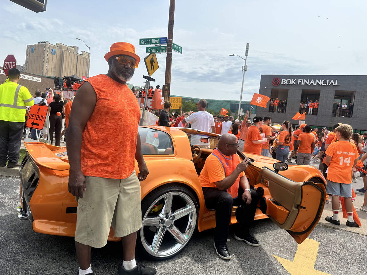 Local Mark Nolen poses with his Corvette as his friend sits in the passenger seat. Nolen loves the color orange, which is why he chose to attend the parade.