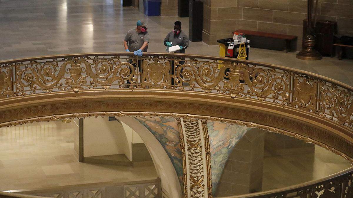 A cleaning crew disinfects a railing inside the Missouri Capitol rotunda Monday, April 27, 2020, in Jefferson City.