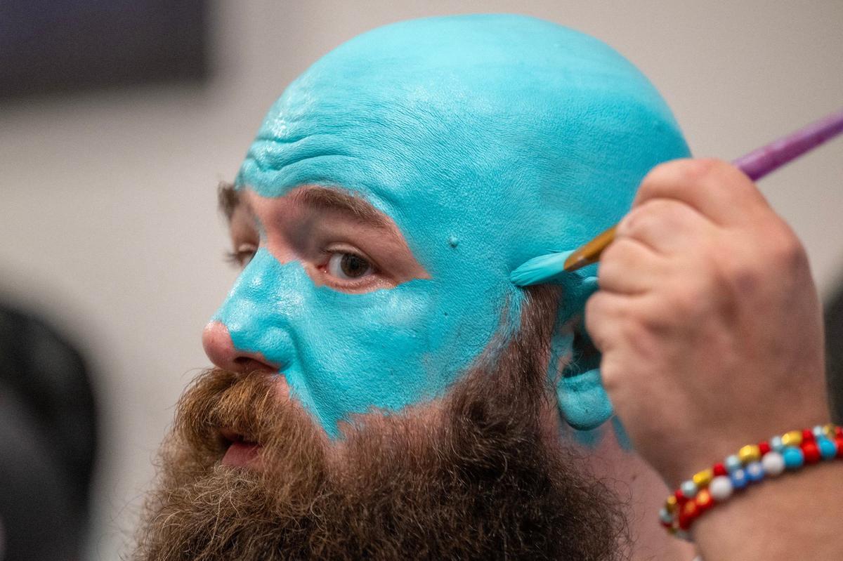 Richard Harper applies teal face paint to his face as he gets ready at home for an NWSL game between Kansas City Current and Bay FC on Saturday, April 20, 2024, in Kansas City.