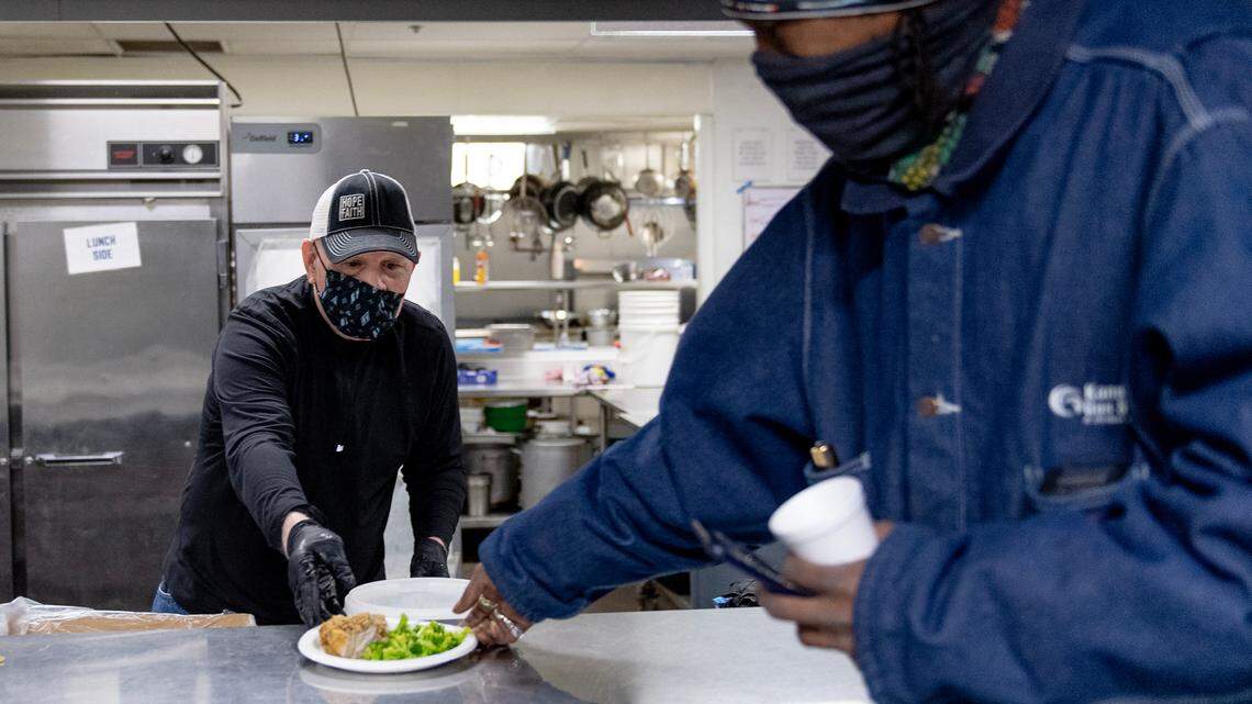 Randy Kellam serves a meal to a man at Hope Faith on Dec. 21, 2022, in Kansas City.