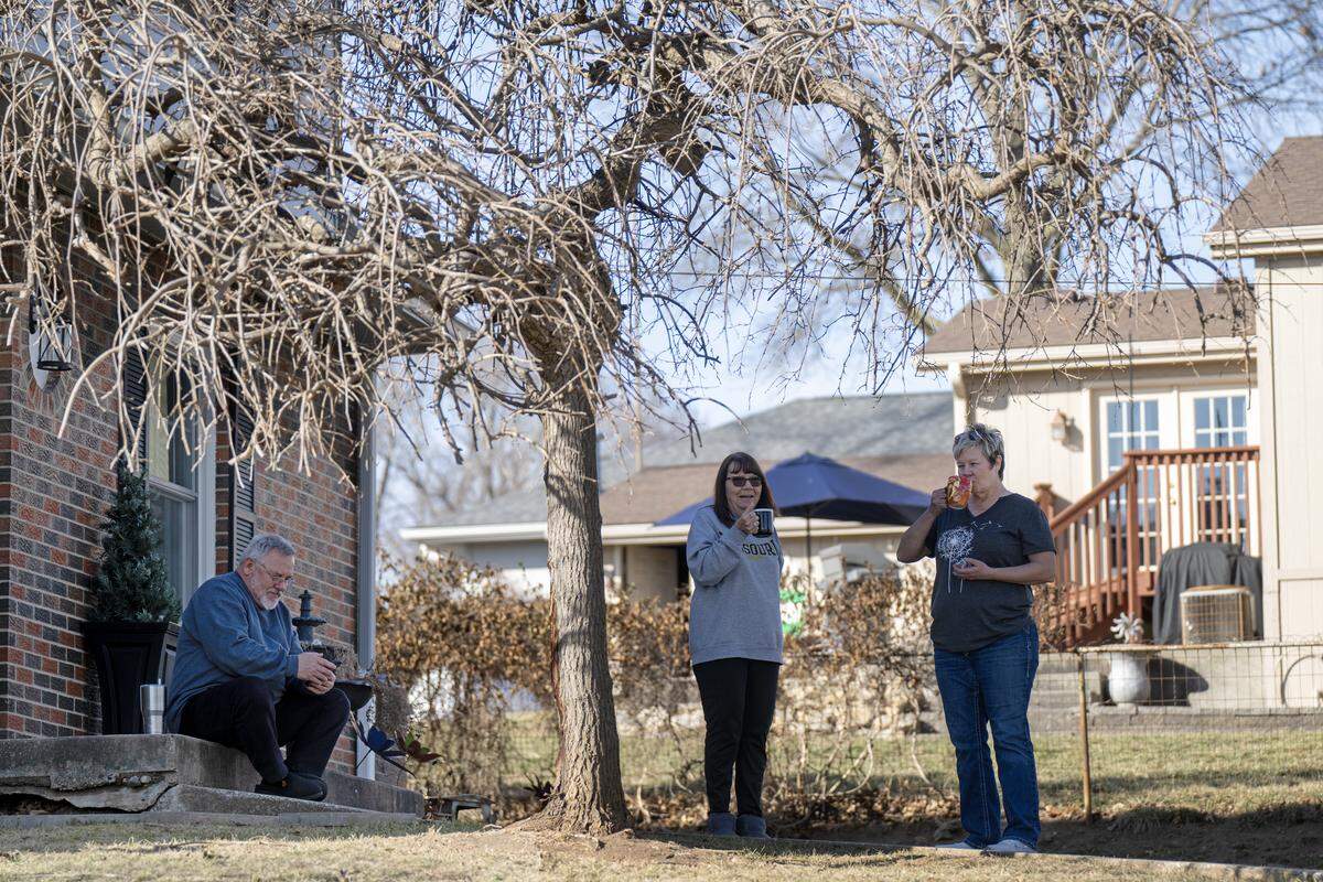 “It's normally very quiet out here… we all try to help each other out… we just have get‑togethers, bonfires,” said Mary Hoff, center, who had coffee outdoors with her neighbor, Dawn Hahnfeld, right, on Friday, Feb. 13, 2026. “It's just a quiet little piece of heaven out here in Independence is what it is.” Howard Hoff, left, occupied himself looking up something on his phone. The residents of Bly road are opposed to a proposed 400-acre, $6.6 billion AI data center across the street from their homes.