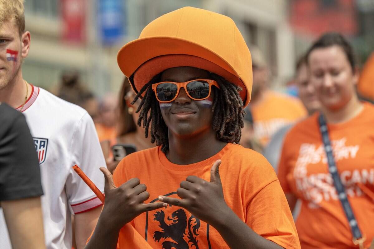 A fan wears an oversized hat and sunglasses while participating in the Orange Walk on Thursday, June 25, 2026, in Kansas City.