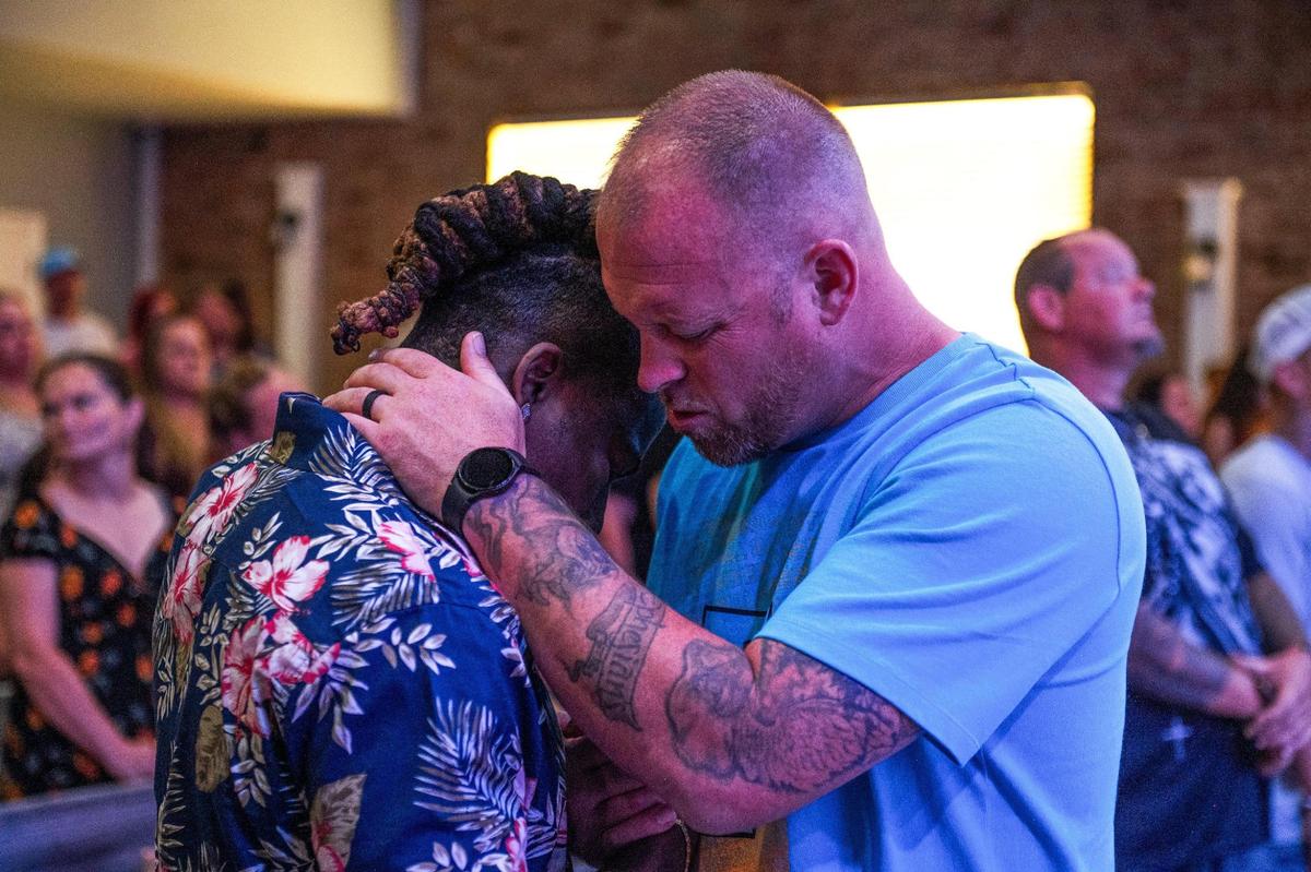 John Roddy, left, is embraced by Pastor Adam Brown while they pray. Roddy says his faith, as well as therapy, help him heal.