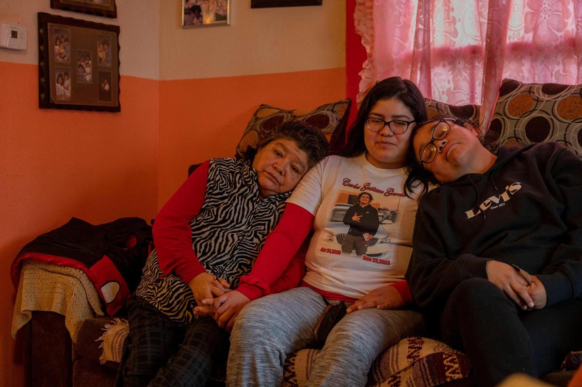 Miriam Garcia, left, her granddaughter Itati Becerra, center, and her daughter Amapola Garcia sit together in the living room of her home to speak about her grandson, Carlos Garcia in Kansas City, Kansas. Carlos was fatally shot outside of Miriam’s home on Dec 22, 2021.