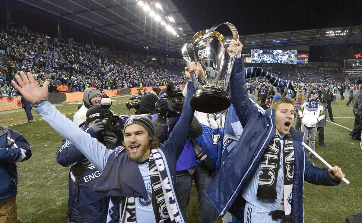 Sporting KC’s Graham Zusi (left) and Matt Besler celebrated with the MLS Cup on their home field after defeating Real Salt Lake in the MLS Cup final on Dec. 7, 2013.