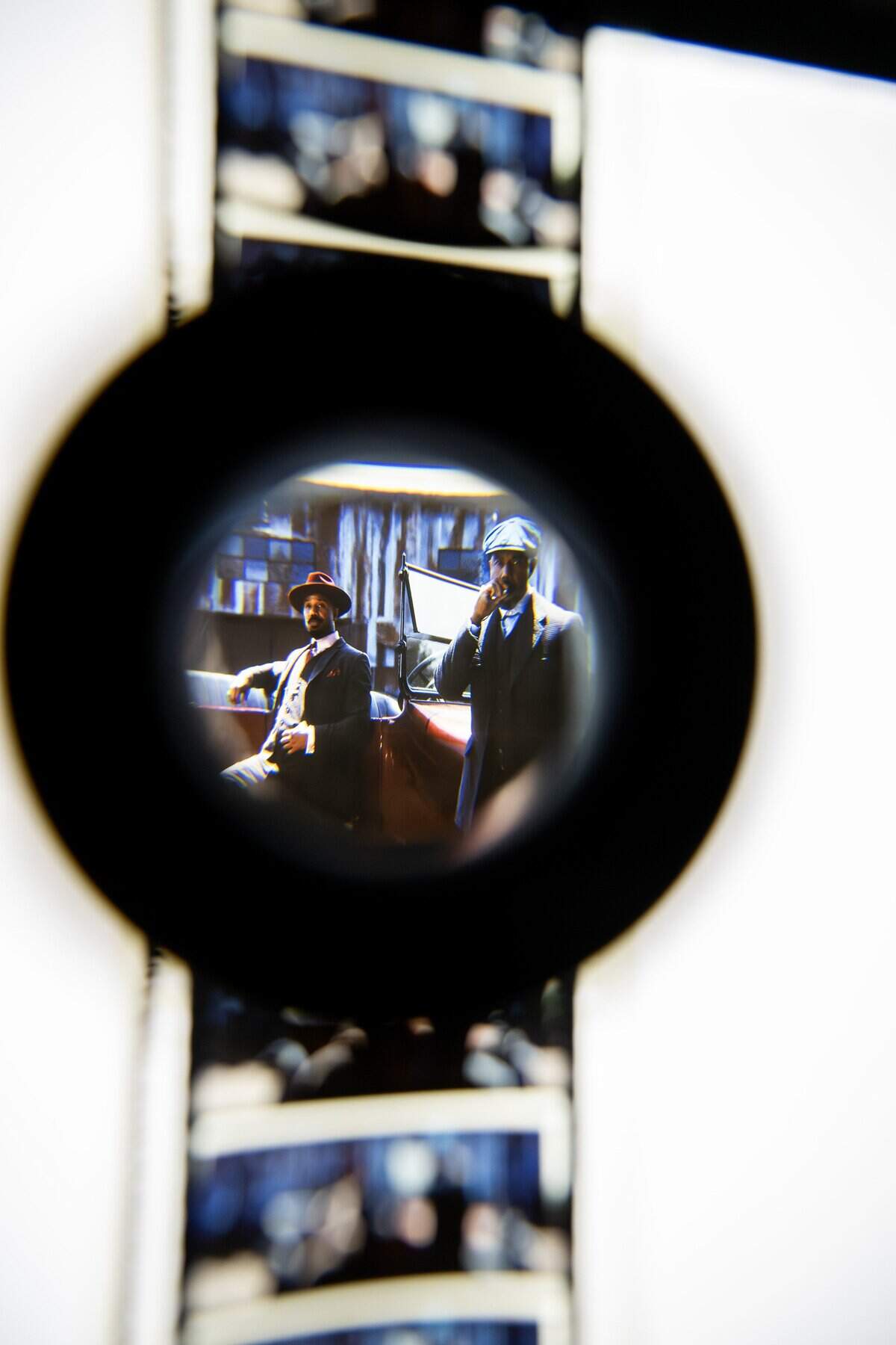 A 70mm film reel is threaded under a light as a single frame is inspected with a magnifying glass during a screening of “Sinners” at Screenland Armour Theatre on Friday, March 27, 2026, in North Kansas City.