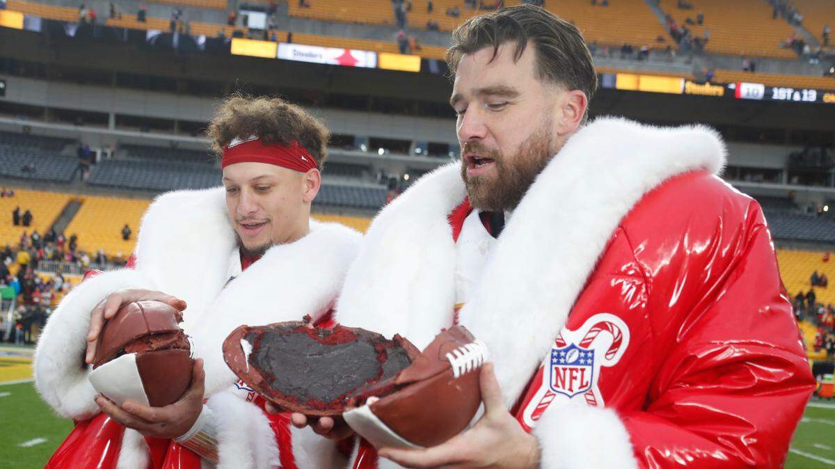 Kansas City Chiefs quarterback Patrick Mahomes (left) and tight end Travis Kelce (right) open their Netflix Christmas Game Day cake after the Chiefs defeated the Pittsburgh Steelers at Acrisure Stadium.