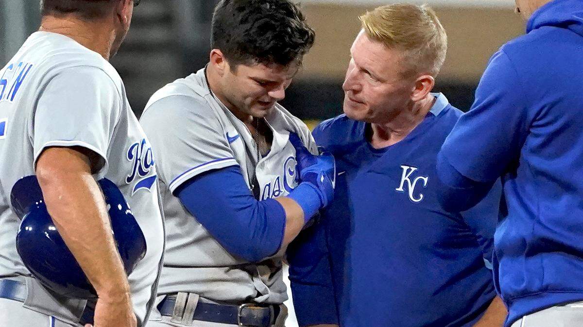 Kansas City Royals’ Andrew Benintendi holds his left shoulder and is checked by a member of the training staff after stealing second during the fourth inning of the team’s baseball game against the Chicago White Sox on Tuesday, Aug. 3, 2021, in Chicago. Benintendi left the game. (AP Photo/Charles Rex Arbogast)