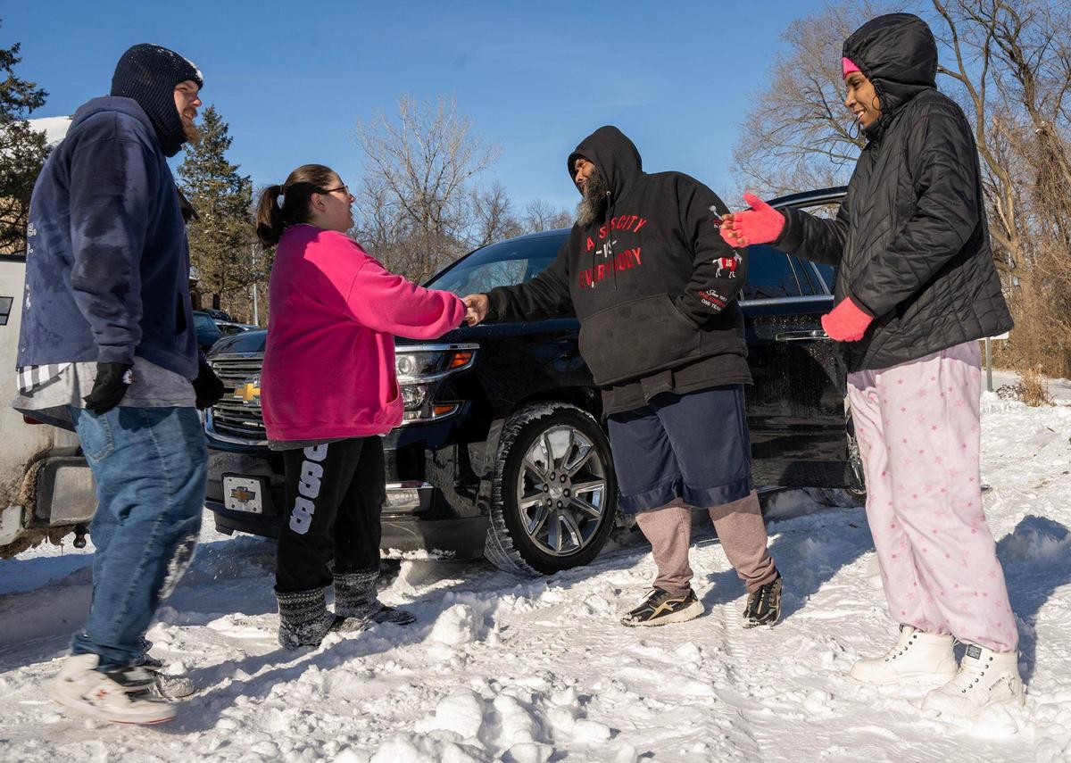Corey Sutton and his wife, Summer Gifford, both age 30, from left, have spent three days traveling the Kansas City area and helping people in need following a major snow storm. Kendall Amos and his niece, Mia Ford-Bailey, thanked the couple after Sutton pulled their truck from a snowbank Tuesday in Kansas City, Kan.