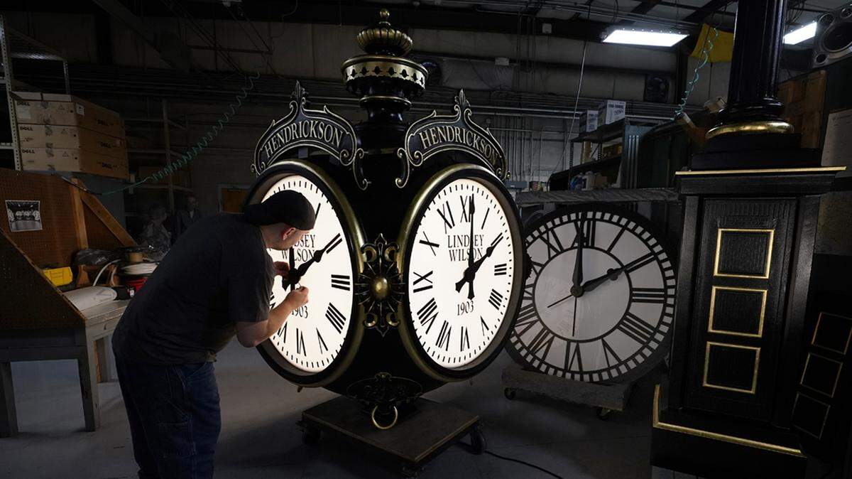 Dan LaMoore adjusts the hands on a Seth Thomas Post Clock at Electric Time Company, Friday, Oct. 23, 2020, in Medfield, Mass. Daylight saving time ends at 2 a.m. local time Sunday, Nov. 1, 2020, when clocks are set back one hour. (AP Photo/Elise Amendola)