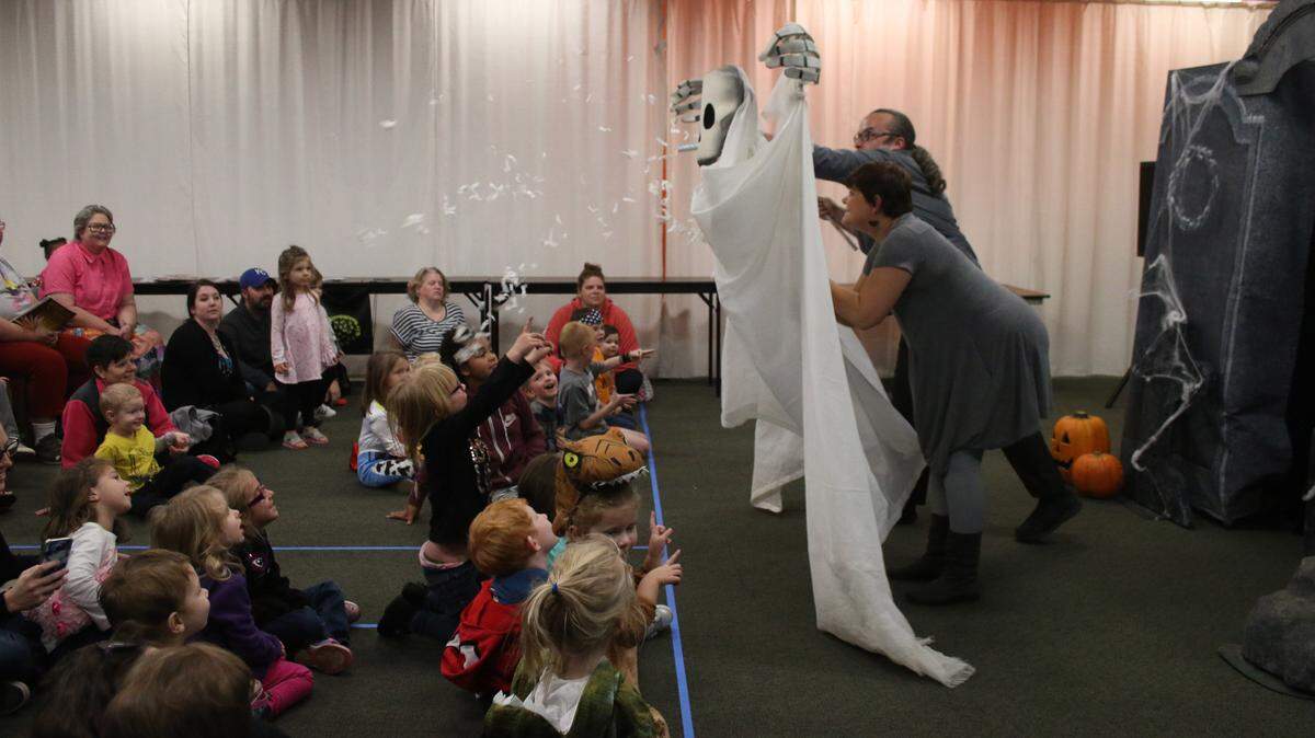 Heather Nisbett-Loewenstein and Justin Howe work together to operate a giant skeleton puppet as it throws confetti over the audience at the Lee’s Summit branch of the Mid-Continent Public Library.