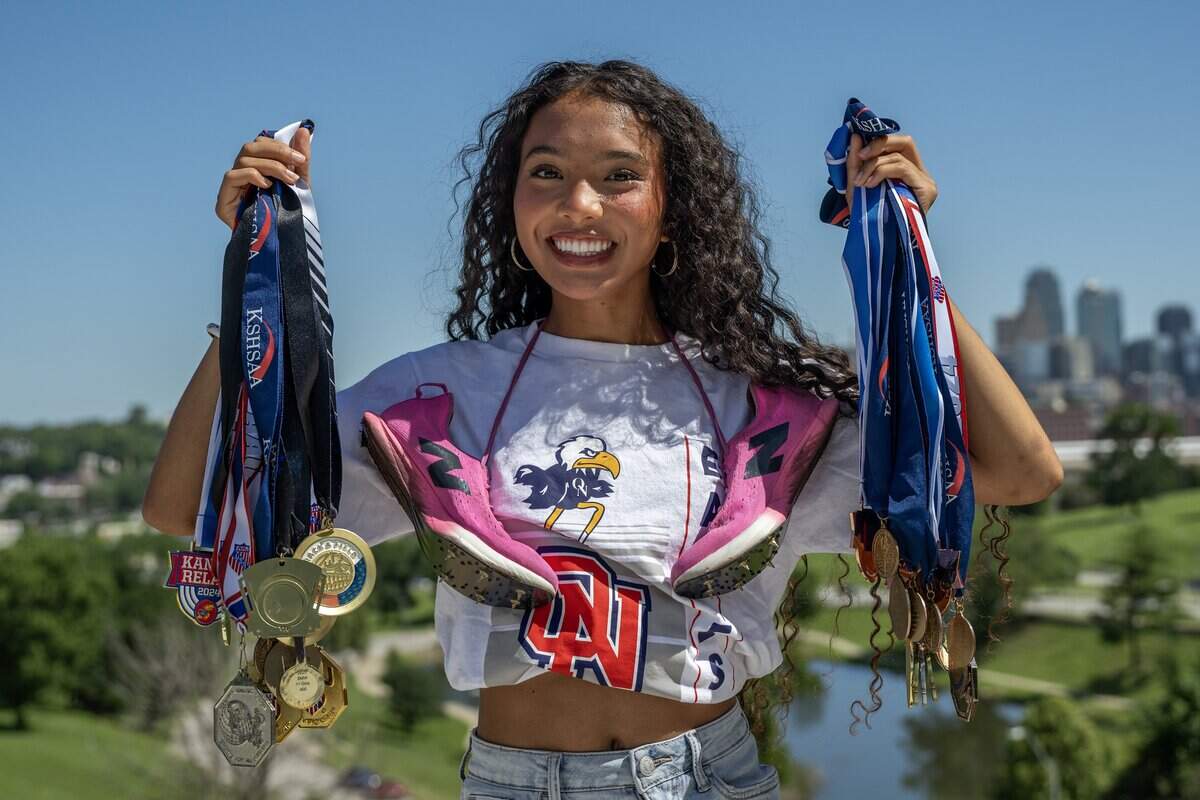 Scholar-Athlete Award recipient Avani Hocker Singh holds up her medals as she poses for a portrait with track spikes draped around her neck on Monday, June 15, 2026, in Kansas City.