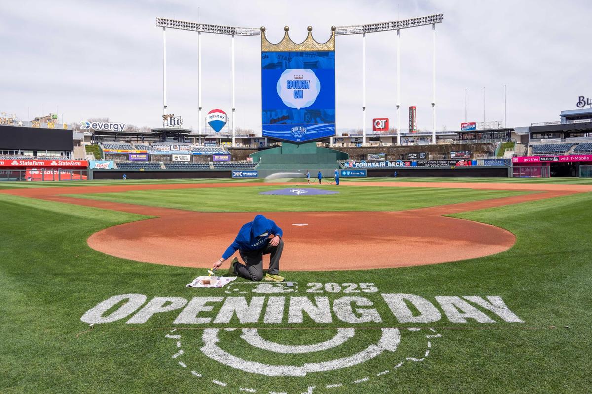 A Royals grounds crew worker paints lettering for the MLB Opening Day logo on the field at Kauffman Stadium on Tuesday, March 25, 2025. Crews worked throughout the day to prepare for Opening Day for the Kansas City Royals.