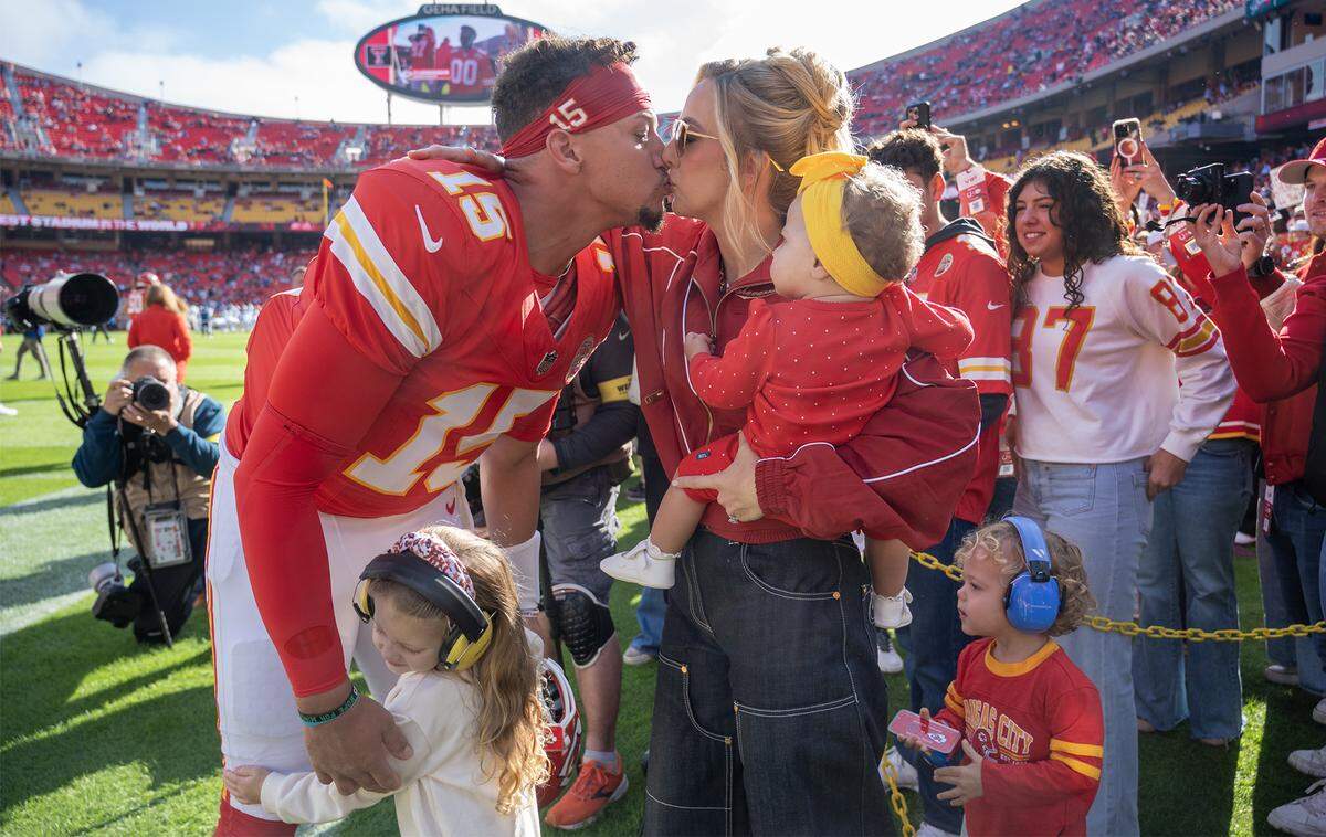 Kansas City Chiefs quarterback Patrick Mahomes (15) kisses his wife, Brittany Mahomes, who holds Golden Raye, as Sterling Skye hugs her dad and Patrick "Bronze" Lavon III, looks on before the kickoff in the game against the Indianapolis Colts on Sunday, Nov. 23, 2025 at GEHA Field at Arrowhead Stadium in Kansas City. 