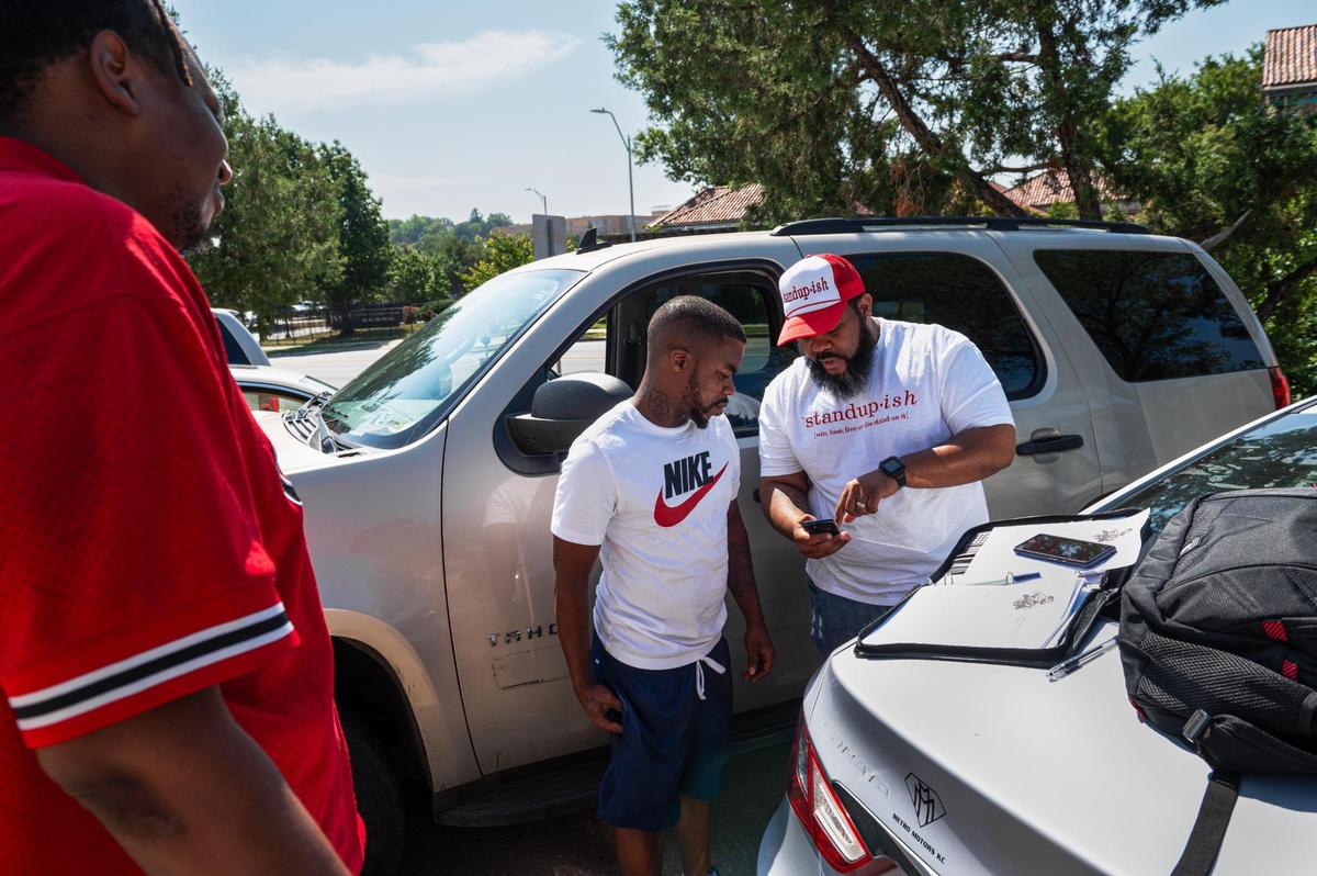 Outside the corrections department, Dontae Hollimon, left, and Tyrese Campbell get help from Andre Harris in filling out a job application.
