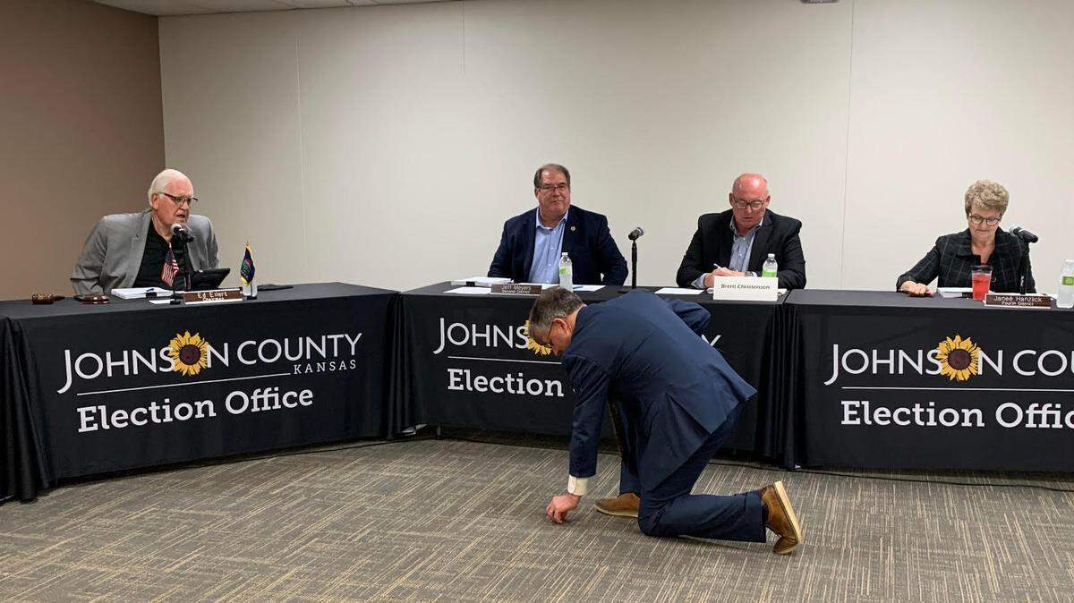 Johnson County Election Commissioner Fred Sherman reaches down for a coin after it was used to determine the winner of the Republican primary contest for Aubry Township Clerk.