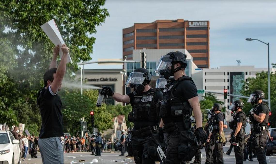 A Kansas City police officer sprays a protester in the face with pepper spray Saturday at the Country Club Plaza.