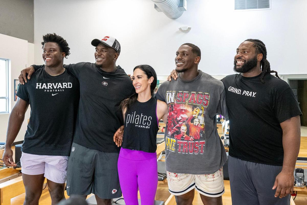 After leading strenuous workout, Kahley Schiller, a certified pilates instructor, takes a photo with Chiefs players including Truman Jones, from left, a defensive end on the practice squad, defensive end Malik Herring and defensive tackles Tershawn Wharton and Derrick Nnadi at Pilates By Kahley on Tuesday, Oct. 29, 2024, in Overland Park.