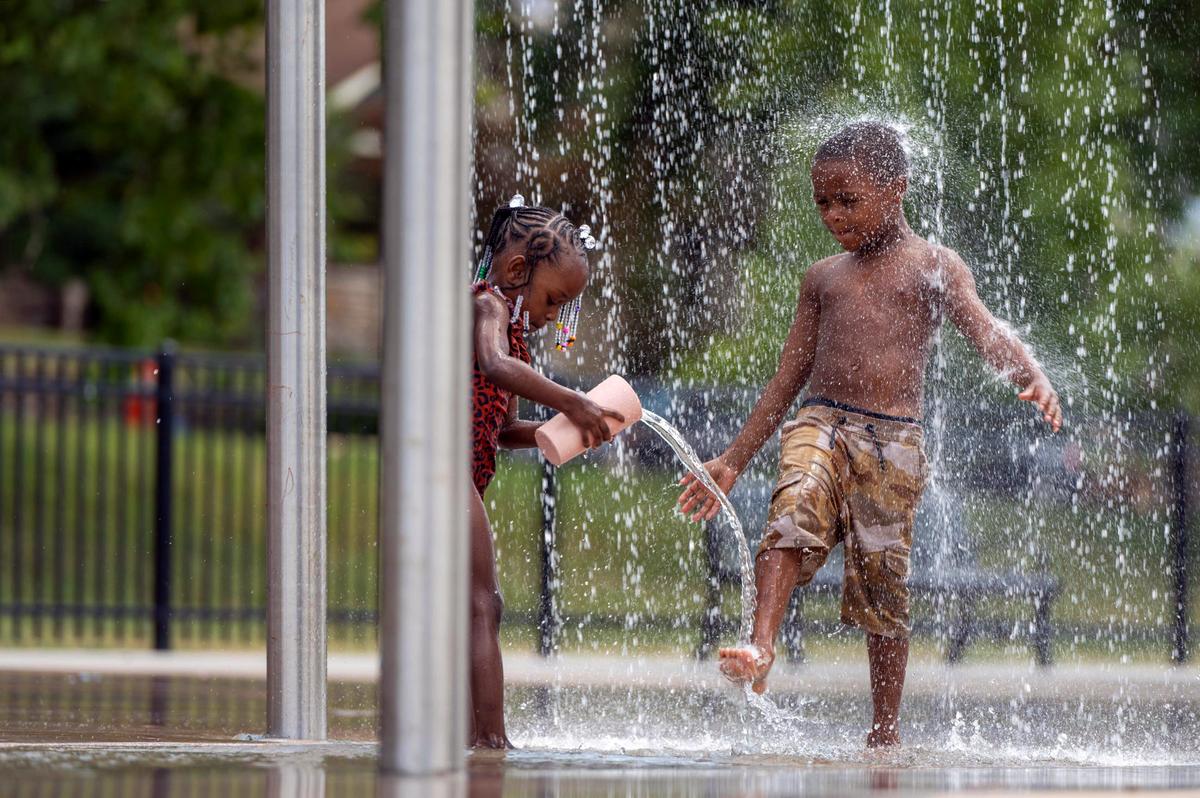Four-year-old Malia Brooks, left, and five-year-old Prince Boyles play under a water fountain at the Sprayground in Gillham Park on Monday, July 18, 2022. Kansas City is expected to see temperatures as high as 100 degrees or above for several days this week.