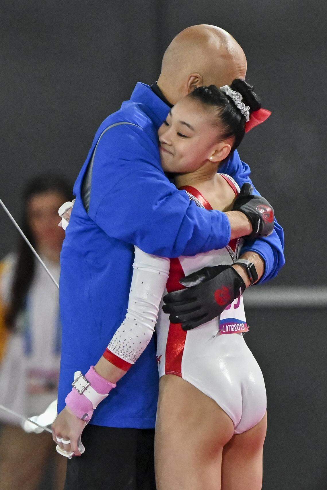 Leanne Wong is hugged by her coach, Al Fong, after a silver medal-winning routine at the Pan-American Games in Lima, Peru, on July 30, 2019.