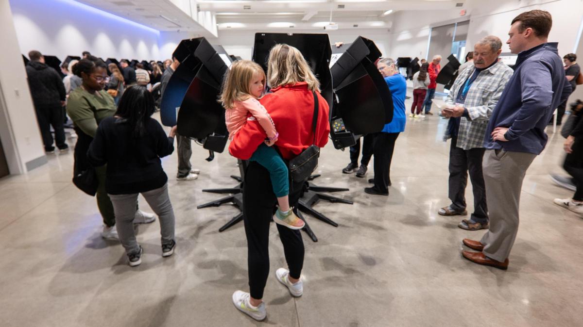 A mother holds her daughter while casting her ballot during advanced voting Monday at the Johnson County Arts and Heritage Center in Overland Park.