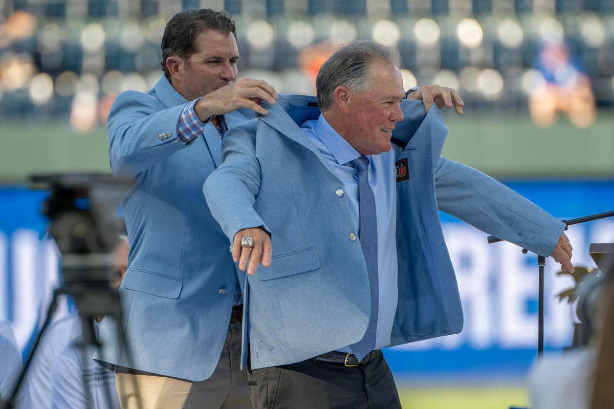 Former Kansas City Royals manager Ned Yost receives his Hall of Fame coat from former first baseman Michael Sweeney during his induction ceremony into the Kansas City Royals Hall of Fame at Kauffman Stadium on Saturday, Sept. 2, 2023, in Kansas City.