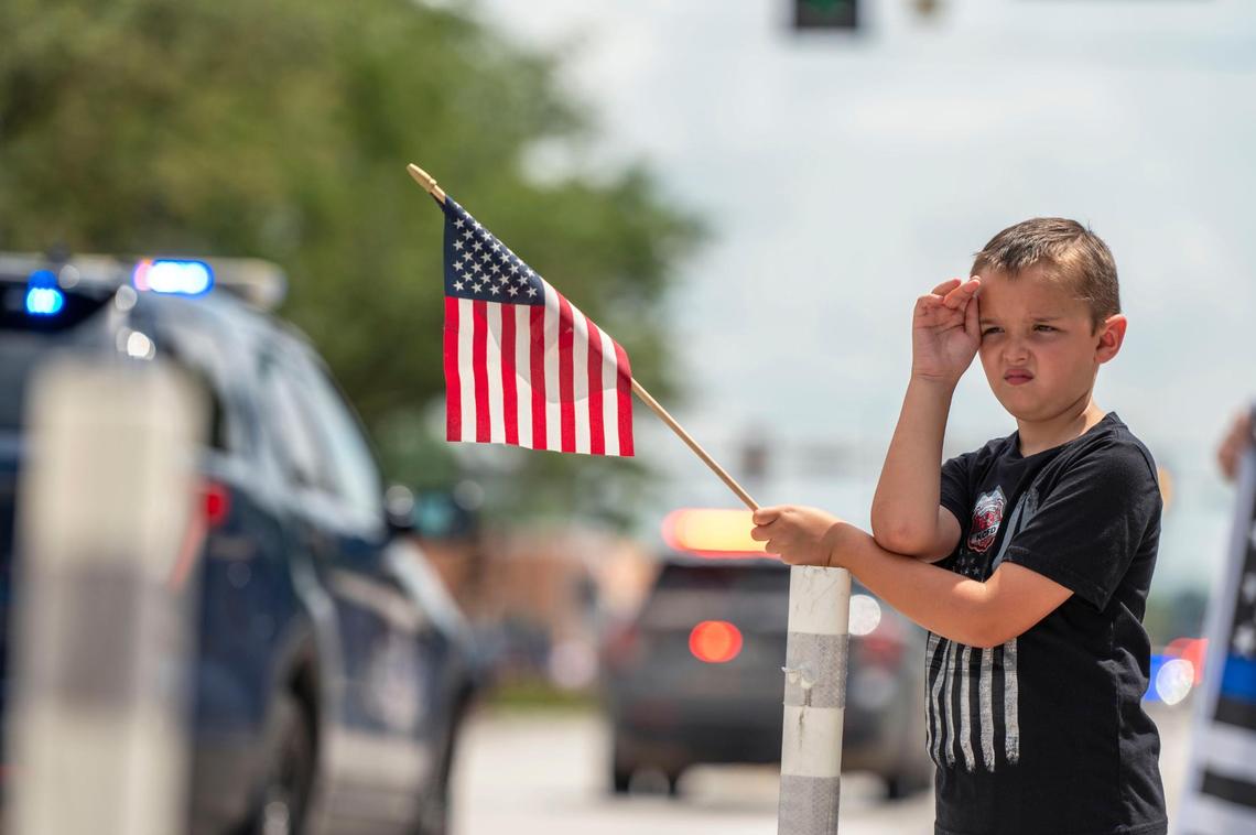 Eight-year-old Will Van Kirk salutes as the funeral procession for North Kansas City police officer Daniel Vasquez passes by on Wednesday in North Kansas City.