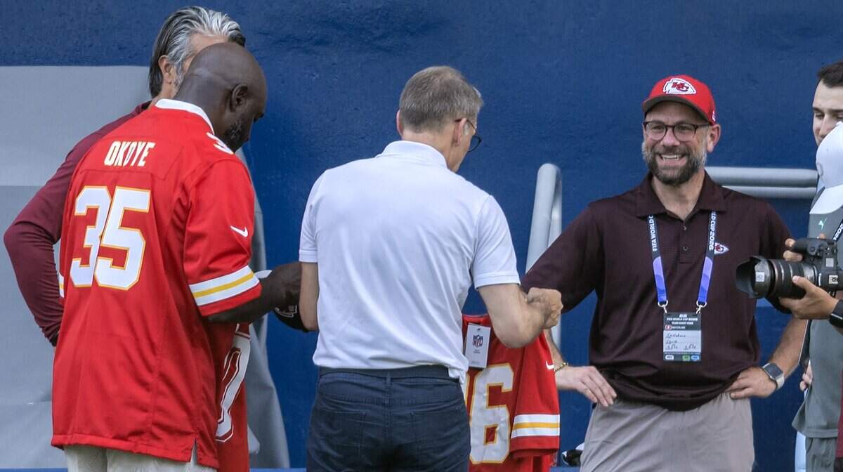 Former Kansas City Chiefs fullback Christian Okoye, left, presents a Chiefs jersey to members of the Switzerland national soccer team during practice at Sporting Park on Thursday, July 9, 2026, in Kansas City, Kansas.