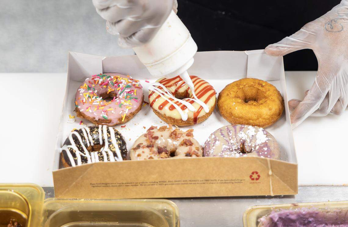 James Frazier, an employee at the Lee’s Summit Duck Donuts shop, prepares a box of donuts on Thursday, April 23.