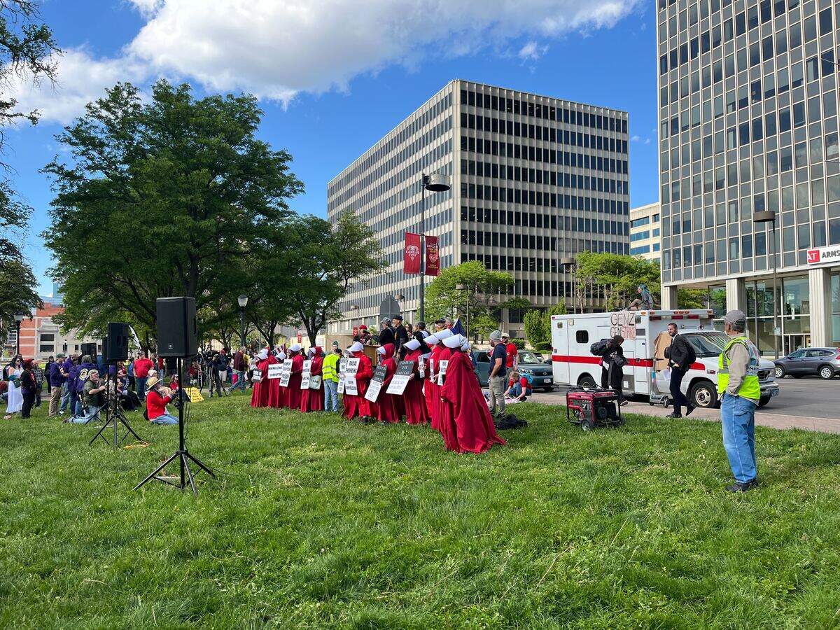 Some protesters wear “Handmaids Tale” style outfits as a May Day protest for workers rights begins Friday, May 1.