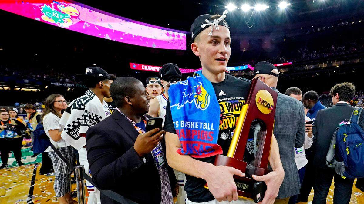 Kansas forward Mitch Lightfoot (44) carries the National Championship trophy after the Jayhawks beat North Carolina in the NCAA Tournament championship game at Caesars Superdome in New Orleans on April 4, 2022.