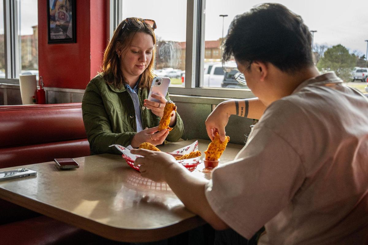Kansas City Star journalists Alison Booth, left, and Irvin Zhang prepare to eat a platter of Spanky’s famous fried cheese in Lubbock, Texas.