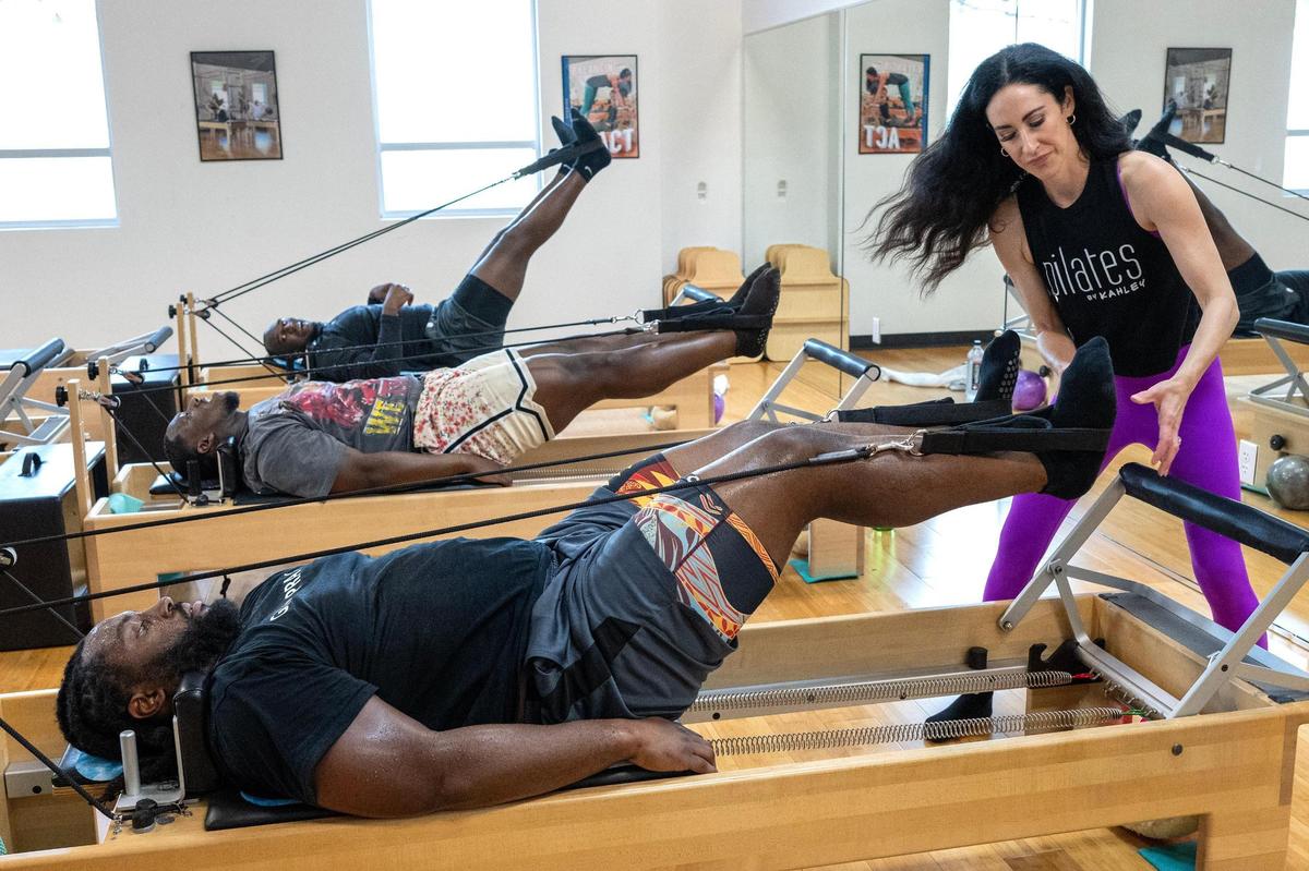 Instructor Kahley Schiller guides Chiefs defensive tackle Derrick Nnadi, as defensive tackle Tershawn Wharton and defensive end Malik Herring, as they work out on pilates reformer beds at Pilates By Kahley on Tuesday, Oct. 29, 2024, in Overland Park. Schiller adjusts Nnadi’s feet during the Chiefs’ training session.
