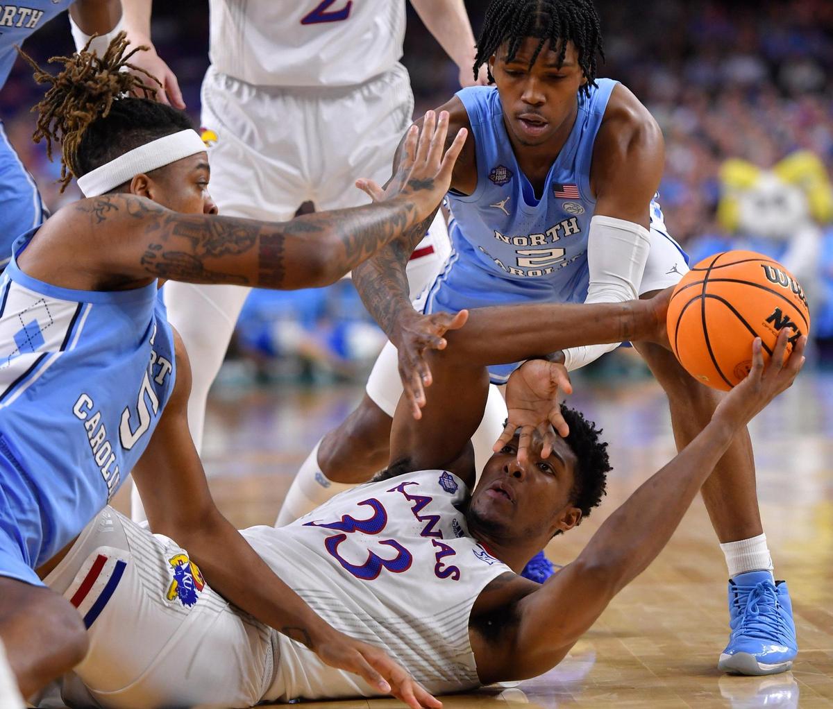 KU’s David McCormack hit the deck for a loose ball along with UNC’s Armondo Bacot and Caleb Love during the first half of Monday night’s NCAA Championship game at the Superdome in New Orleans.