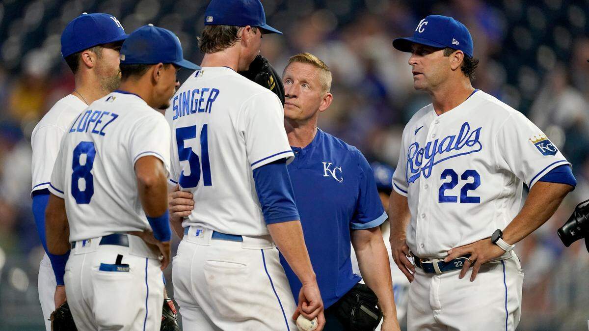 Kansas City Royals trainer Nick Kenny, second from right, and manager Mike Matheny (22) talk to starting pitcher Brady Singer before taking him out of the game during the first inning of a baseball game against the Cleveland Indians Tuesday, Sept. 28, 2021, in Kansas City, Mo. (AP Photo/Charlie Riedel)